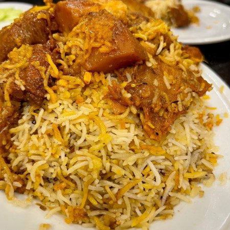 Mutton kacchi biryani served with meat and potatoes piled on top